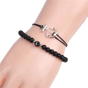 Detail of beaded bracelet set with black matte stones, anchor charm and letter L bead
