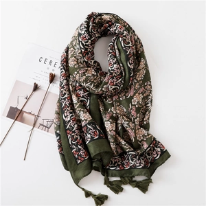 Détail d'une écharpe florale vert foncé avec pompons et imprimé ethnique vintage