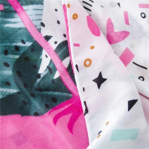 Gros plan d'une écharpe boho en coton et lin avec motif flamant rose, feuilles et glands