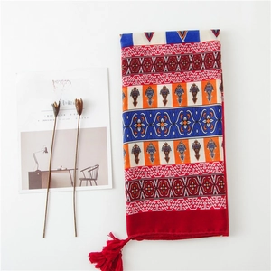 Détail d'une écharpe bohème à imprimé floral avec glands rouges et motifs ethniques
