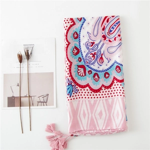 Détail d'un châle bohème avec imprimé paisley et pompons roses décoratifs sur le bord