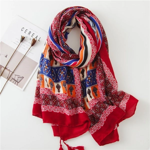 Détail d'un châle rouge en coton et lin avec imprimés bohèmes et pompons frangés