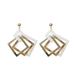 Retro geometric acrylic earrings featuring interlocking white and gold squares in a long style