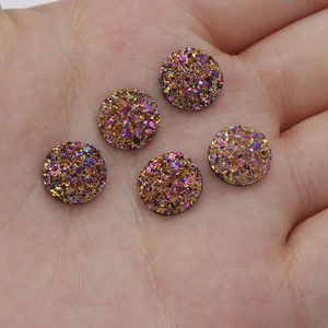 Close-up of 10mm gold-purple starry resin druzy cabochons on a hand for DIY jewelry