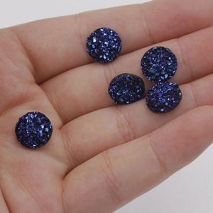 Close-up of 10mm dark blue resin drusy cabochons held in hand to show size and sparkle