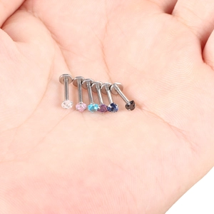 Close-up of six stainless steel labret studs featuring multicolor heart-shaped zircons