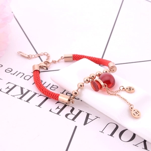 Dettaglio del bracciale in corda rossa intrecciata con ciondoli oro e monete