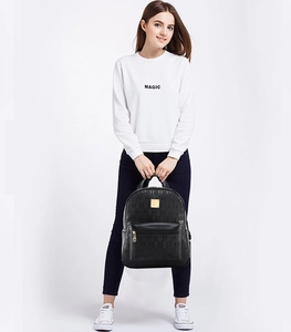 Close-up of black synthetic leather backpack featuring embossed texture and gold metal logo