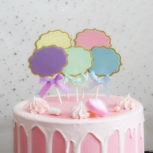 Close-up of cloud-shaped cake toppers with colorful ribbon bows on a pink frosted cake