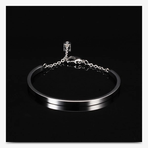 Detailed close-up of a silver U-shaped stainless steel bangle with a heart charm detail