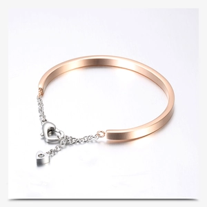 Detail of rose gold and silver U-shaped stainless steel bangle with heart clasp