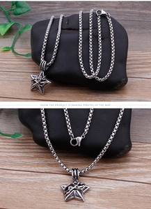 Detailed macro of vintage stainless steel star pendant with box chain on dark rock