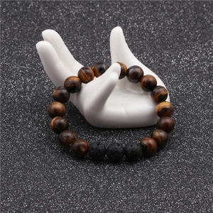 Detailed shot of 10mm tiger eye and black lava stone beaded bracelet on white hand model
