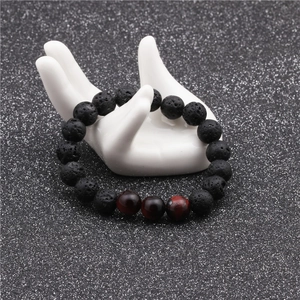 Close-up of 10mm black volcanic lava stone and tiger eye beads on a hand model