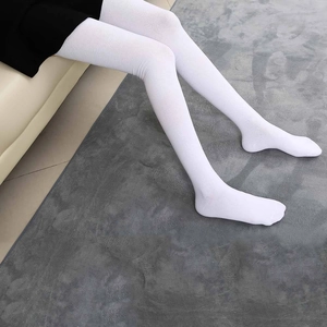 White cotton over-the-knee high socks with knitted texture on model legs over soft rug