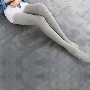Close-up of grey over-the-knee cotton socks showing knit texture on plush carpet
