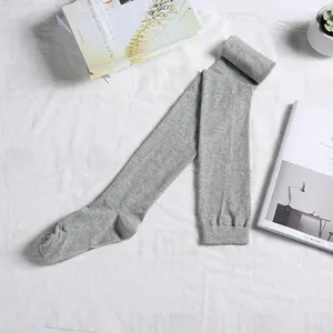 Detail of light grey knitted over-knee high socks with textured marl finish on white fabric