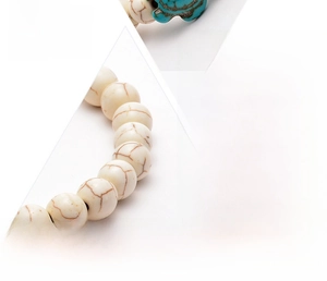 Detailed macro view of handmade turquoise turtle charm and white marble beads bracelet