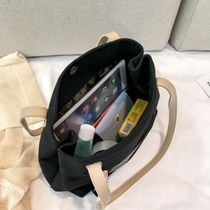 Large black canvas tote bag with beige straps showing spacious interior and magnetic buckle