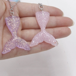 Detailed close-up of gradient resin mermaid tail pendants with shimmering sequins