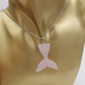 Detail of pink glitter mermaid tail pendant with silver chain on a golden bust