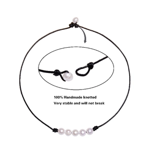 Detail of handmade knotted leather cord necklace with white freshwater pearls