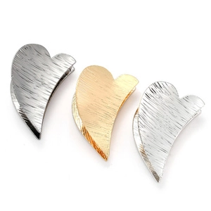 Macro detail of heart-shaped metal hair claws with brushed gold and silver textures