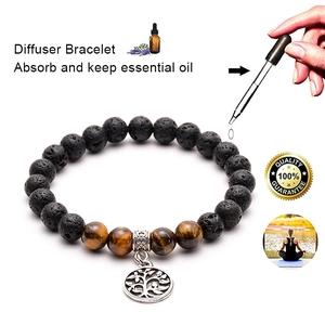 Detail of essential oil dropping onto lava stone diffuser bracelet with tree of life charm