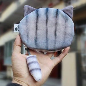 Cute gray striped cat plush coin purse with fuzzy tail pendant held in hand outdoors