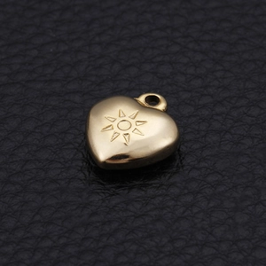 Golden heart-shaped stainless steel pendant with sunburst engraving on leather background