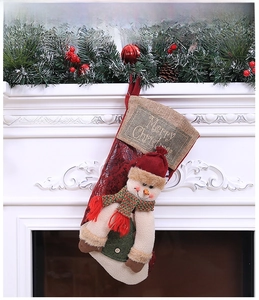 Detail of red Christmas stocking with 3D snowman and pine branches on a white fireplace