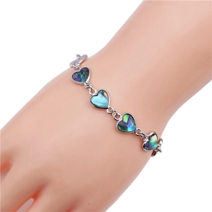 Macro shot of silver heart-shaped bracelet with iridescent abalone shell inlays on wrist