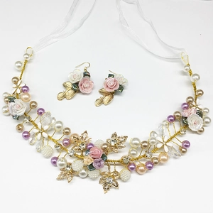 Detail of bridal jewelry set with handmade ceramic flowers and pearls on a white surface