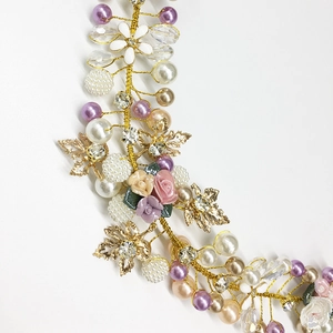 Macro detail of bridal headband with pearls, ceramic flowers and golden leaves