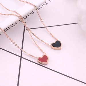 Détail de colliers en or rose avec pendentifs cœur noir et rouge et bordure perlée