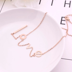 Elegant rose gold LOVE letter necklace in polished titanium steel on a white ceramic dish