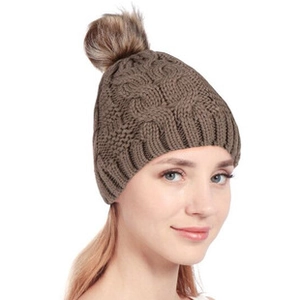 Détail du bonnet en tricot marron avec motif de torsades et pompon en fausse fourrure