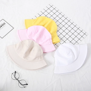 Flat lay of cotton bucket hats in yellow, pink, beige, and white with stitched brims