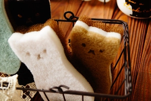 Cat-shaped dish sponges in white and brown colors stored in a black wire basket