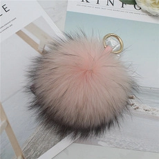 Detailed close-up of fluffy pink and grey faux fur pompom with golden metal clasp