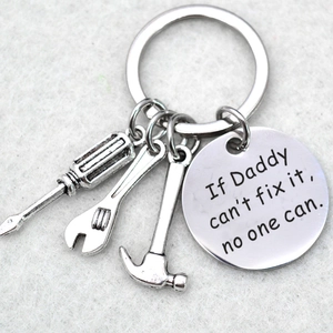 Macro detail of silver stainless steel keychain with tools and Dad fix it engraving