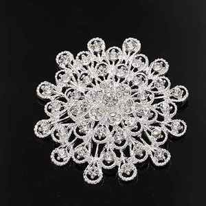 Macro shot of silver rhinestone brooch with symmetrical snowflake pattern on black background