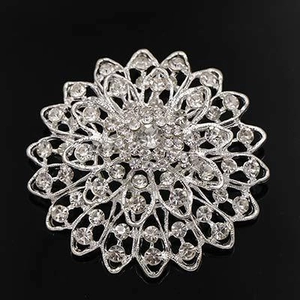 Close-up of a silver flower brooch with sparkling rhinestones on black background
