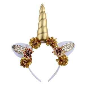 Close-up of a golden unicorn horn headband with shiny sequins and artificial flowers