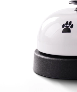 Close-up of white pet training bell with black paw print and non-slip base