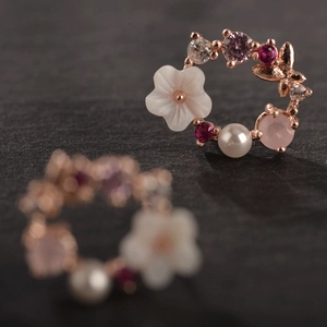 Makroansicht von roségoldenen Blumenohrringen mit Perlen und bunten Kristallen