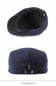 Detailed view of navy knit beret cap interior lining and metal snap button strap