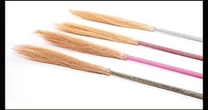 Detail of four colorful witch brooms with metallic glitter handles for Halloween costumes