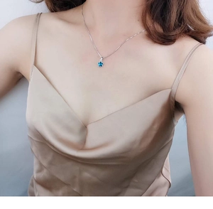 Close-up of minimalist silver necklace with blue star crystal pendant on a model neck