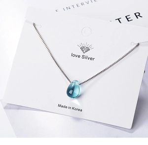 Close-up of blue water drop crystal pendant on silver box chain jewelry card